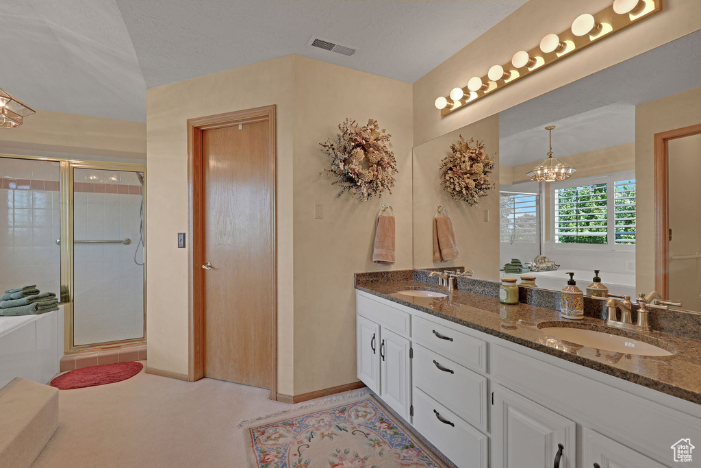 Bathroom with double vanity, a bath, a stall shower, and a chandelier