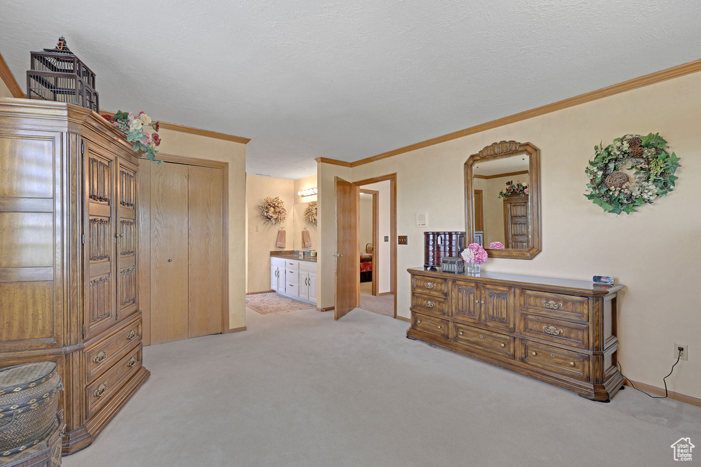 Bedroom featuring light colored carpet, crown molding, ensuite bathroom, and arched walkways