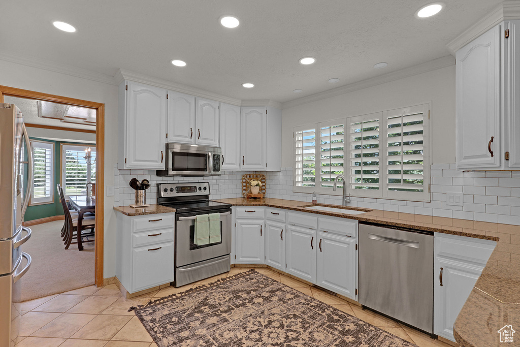 Kitchen with appliances with stainless steel finishes, ornamental molding, stone counters, white cabinetry, and recessed lighting