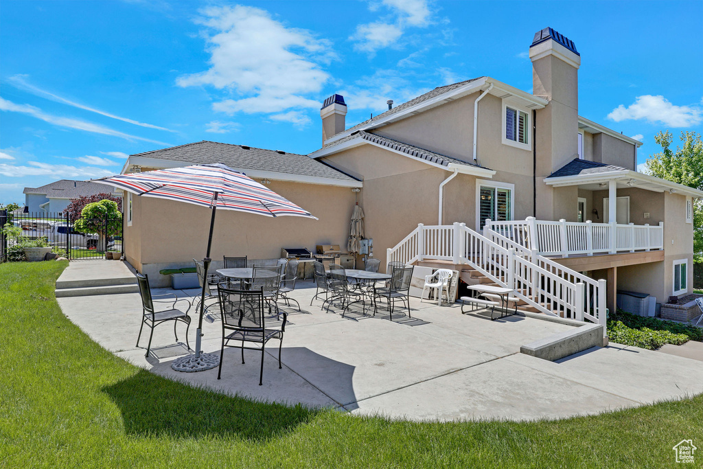 Back of house featuring a chimney, stucco siding, and a patio