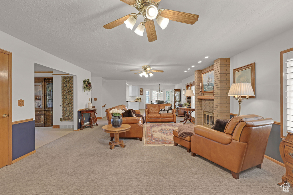 Carpeted living room with ceiling fan and a brick fireplace