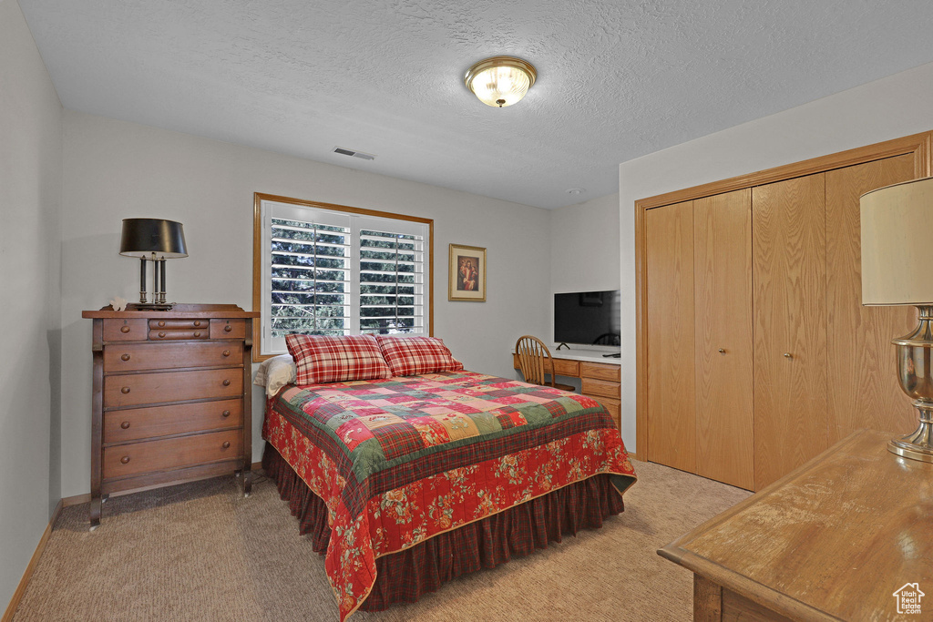 Bedroom featuring light colored carpet, a closet, and a textured ceiling