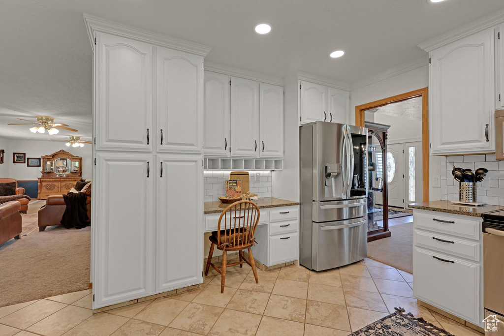 Kitchen featuring stainless steel fridge with ice dispenser, built in study area, light colored carpet, dark stone counters, and recessed lighting