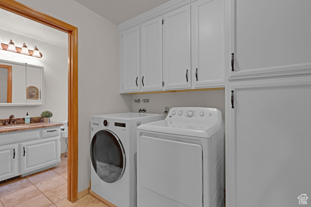 Laundry room with washing machine and dryer, cabinet space, and light tile patterned floors