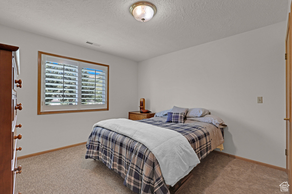 Carpeted bedroom featuring baseboards and a textured ceiling