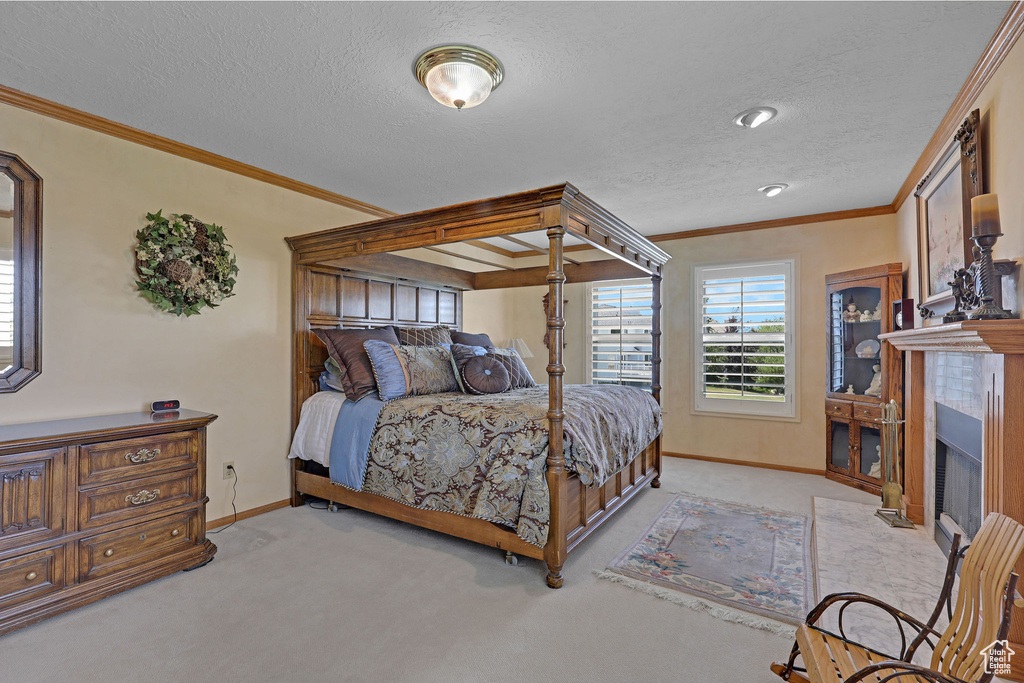 Bedroom with light colored carpet, crown molding, a fireplace with flush hearth, and a textured ceiling