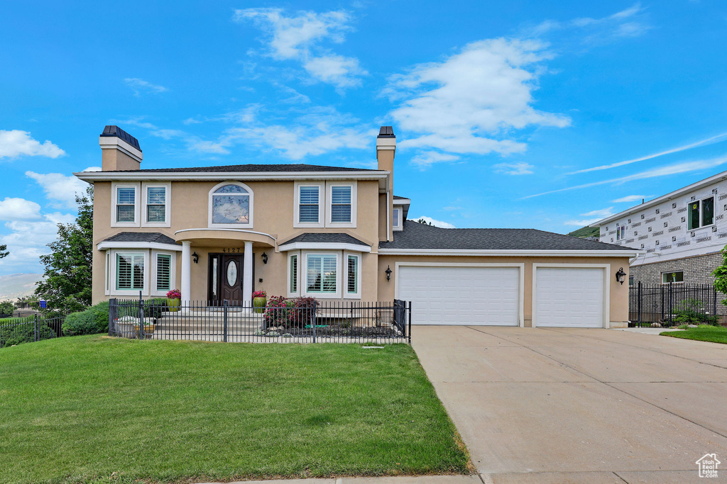 Traditional-style home with a chimney, concrete driveway, stucco siding, and a garage