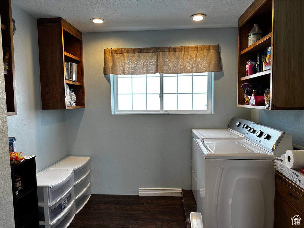 Laundry area with independent washer and dryer, cabinet space, dark wood-style floors, and a baseboard radiator