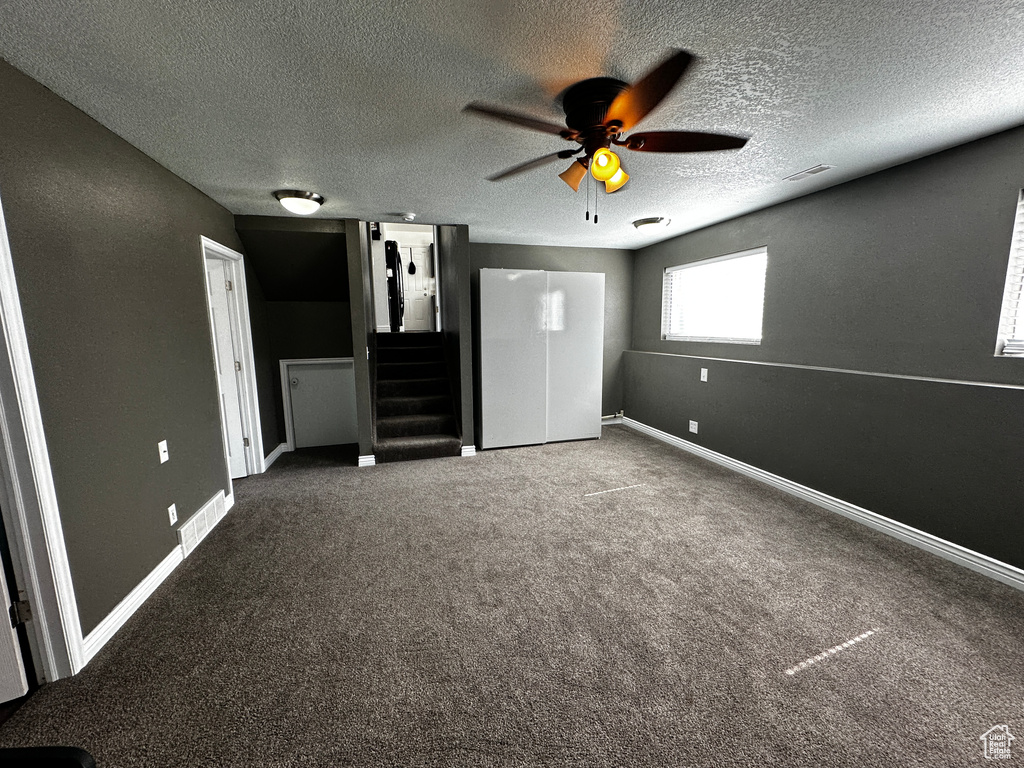 Unfurnished bedroom with a textured ceiling, carpet floors, and a ceiling fan