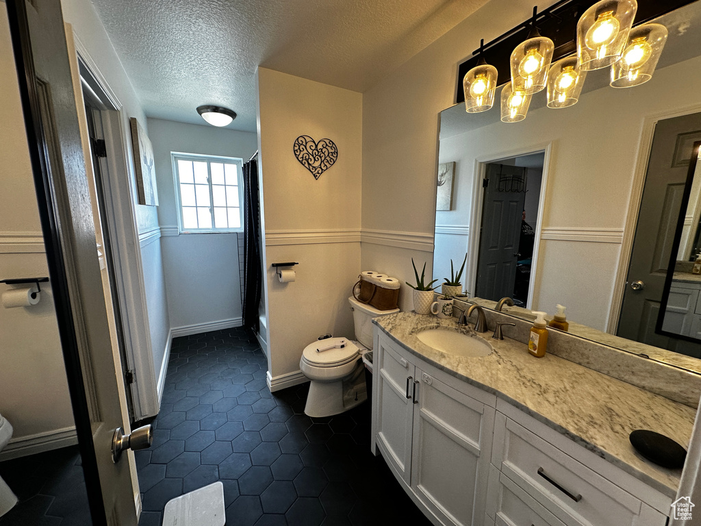 Bathroom featuring vanity, a textured ceiling, curtained shower, tile patterned floors, and a chandelier