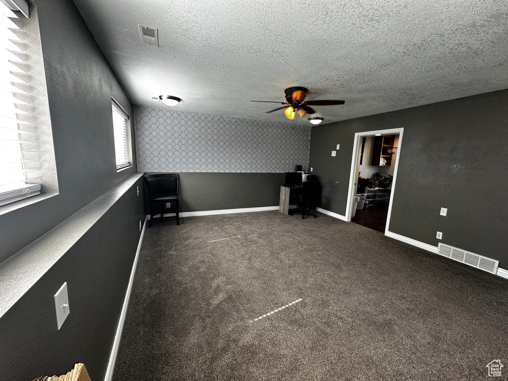 Spare room featuring ceiling fan, a textured ceiling, and carpet floors