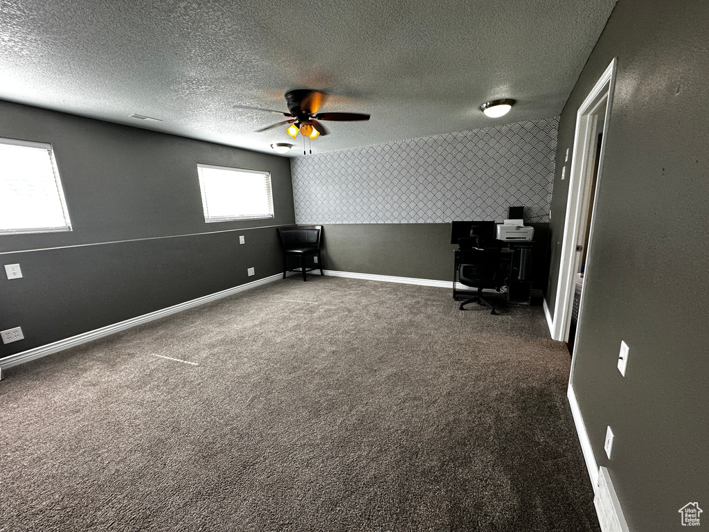 Unfurnished office featuring a textured ceiling, carpet flooring, and a ceiling fan