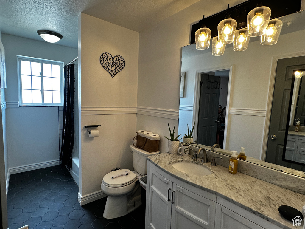 Full bathroom with vanity, tile patterned flooring, a textured ceiling, a chandelier, and shower / tub combo with curtain