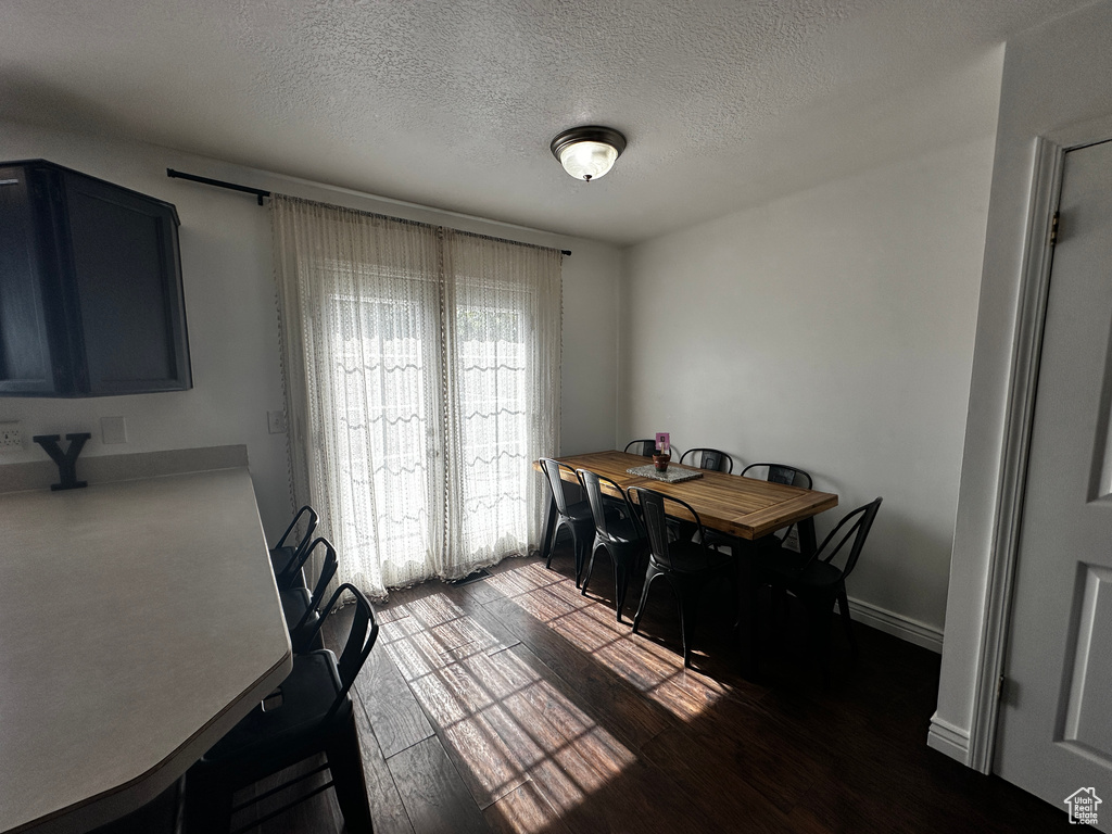 Dining room featuring a textured ceiling and dark wood-style floors