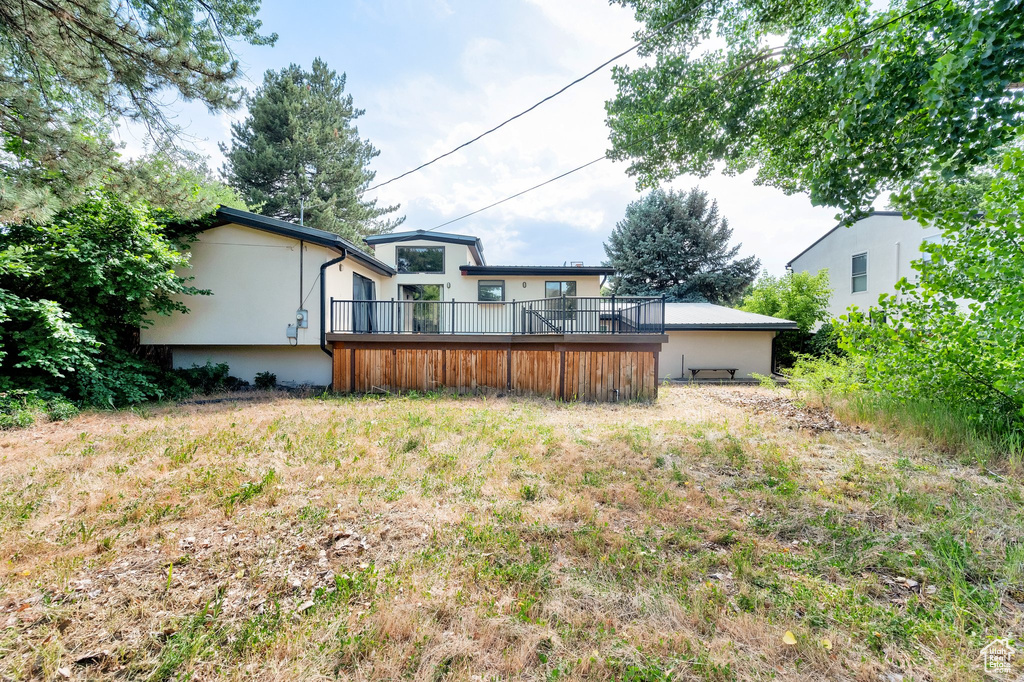 Back of house with stucco siding and a deck