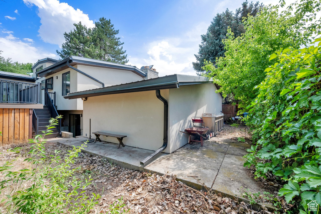 Back of property featuring stairs, stucco siding, and a chimney