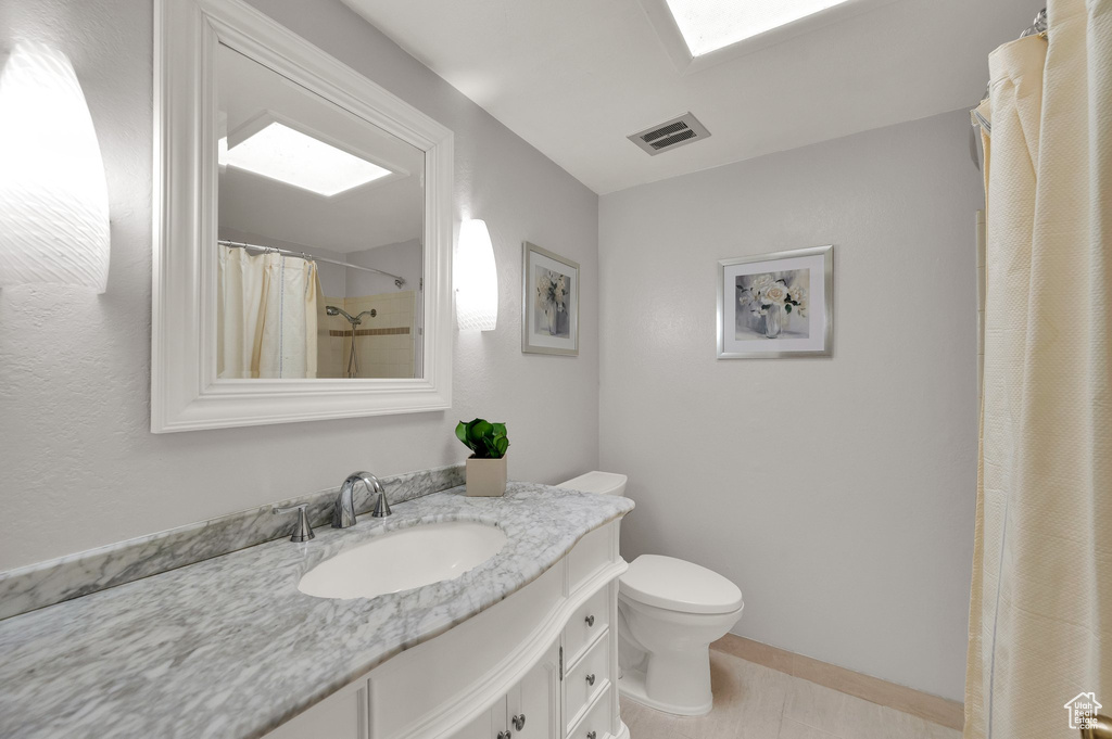 Bathroom with vanity, a skylight, and a shower with curtain