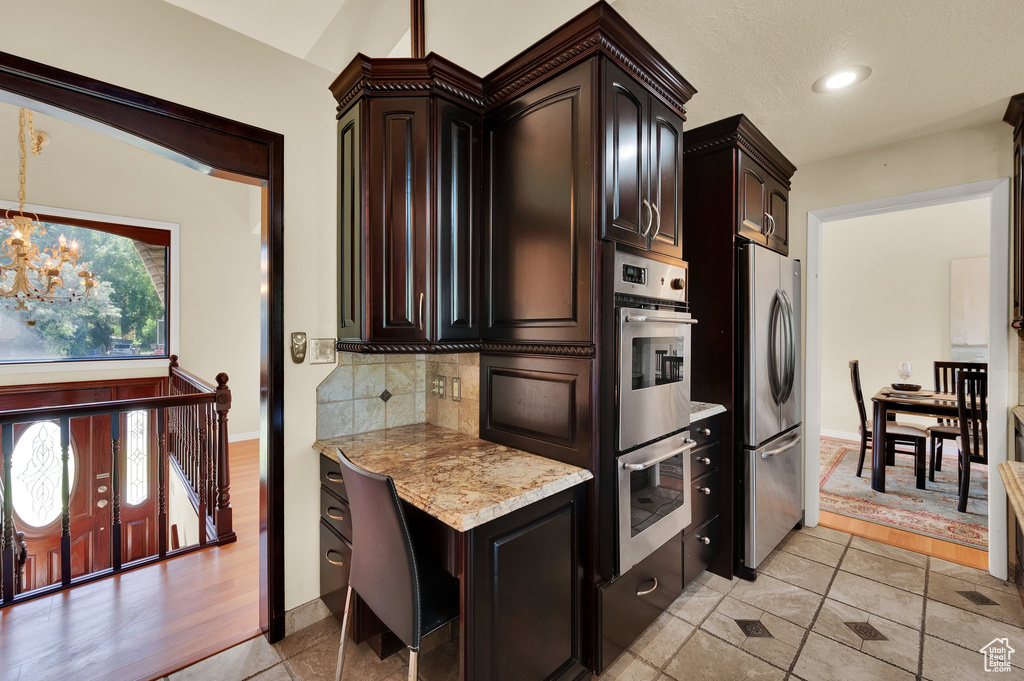 Kitchen featuring appliances with stainless steel finishes, a chandelier, tasteful backsplash, dark brown cabinets, and recessed lighting