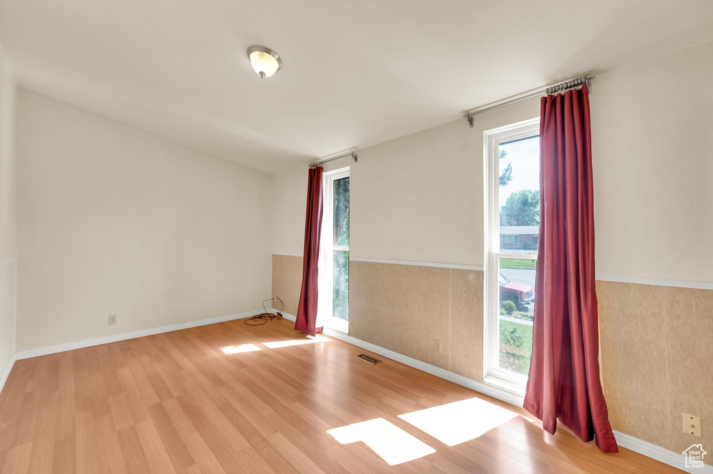 Empty room featuring wood finished floors and wainscoting
