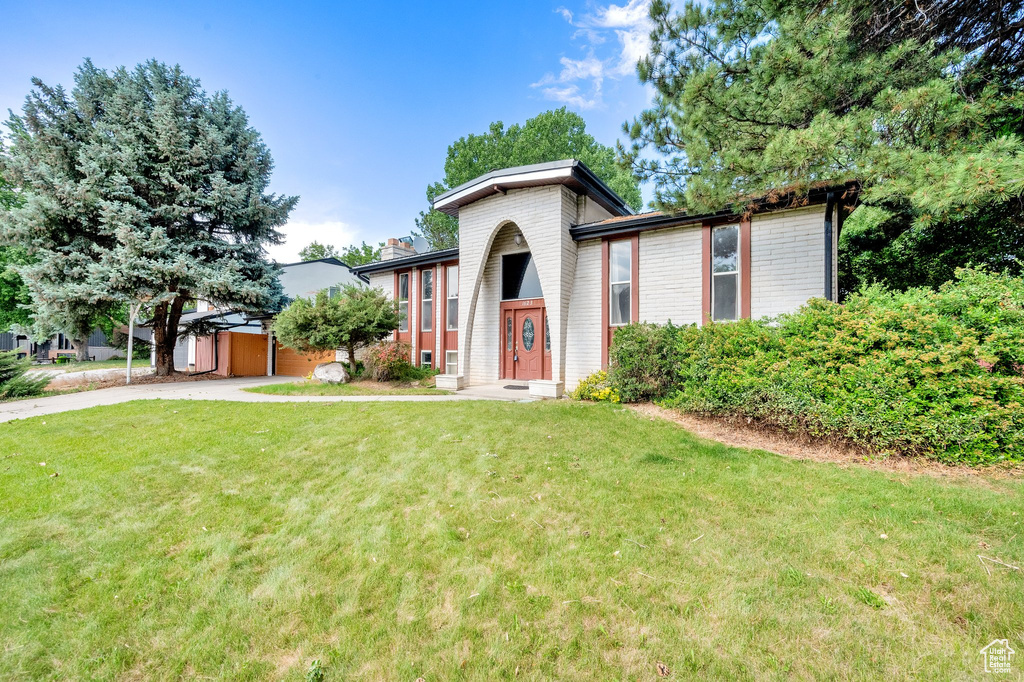 View of front facade featuring a front lawn, driveway, and a chimney