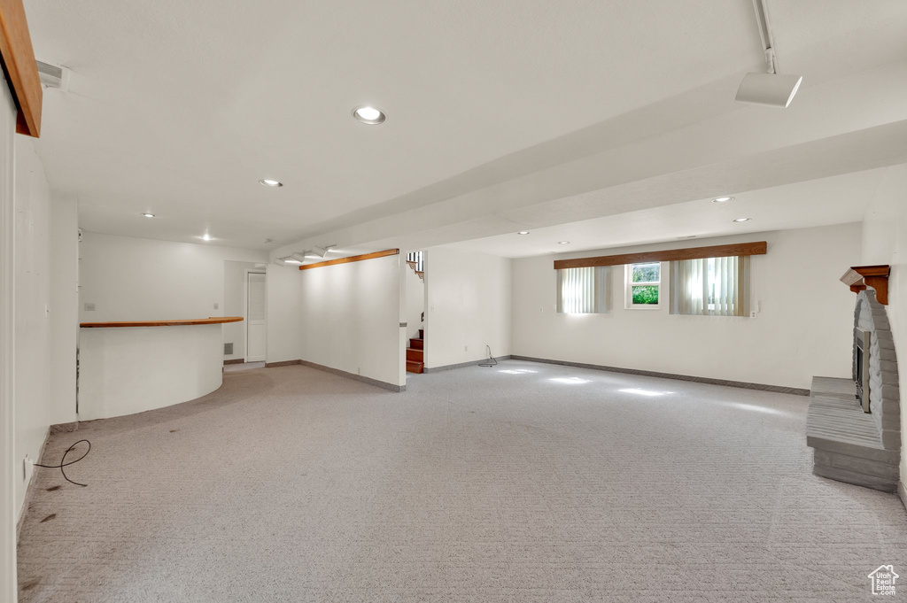 Basement with light carpet, recessed lighting, and a brick fireplace
