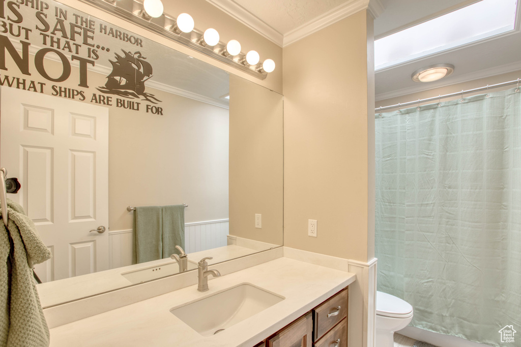 Full bath with vanity, a wainscoted wall, and crown molding