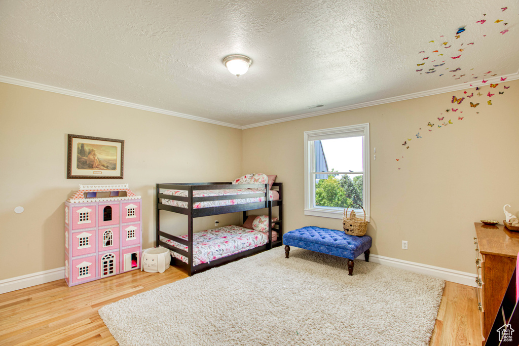 Bedroom featuring crown molding, wood finished floors, and a textured ceiling