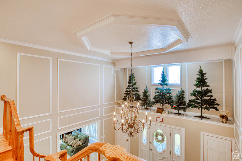 Foyer with a decorative wall, a chandelier, and crown molding