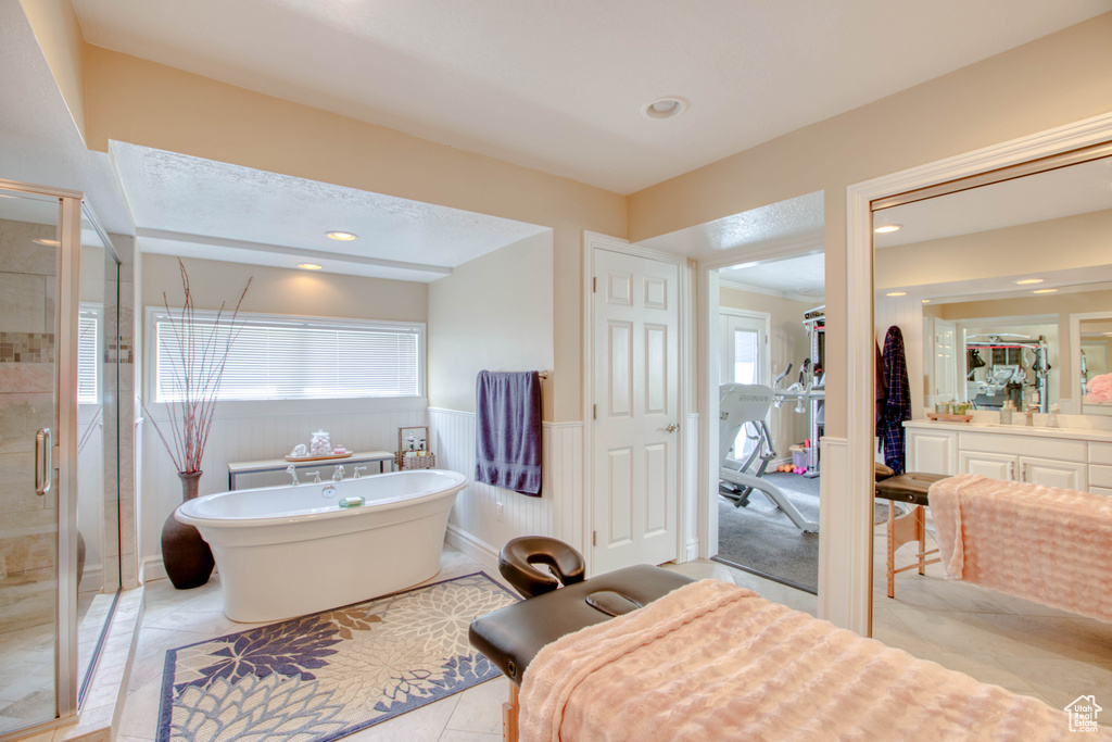 Bathroom featuring a shower stall, a freestanding tub, vanity, wainscoting, and recessed lighting