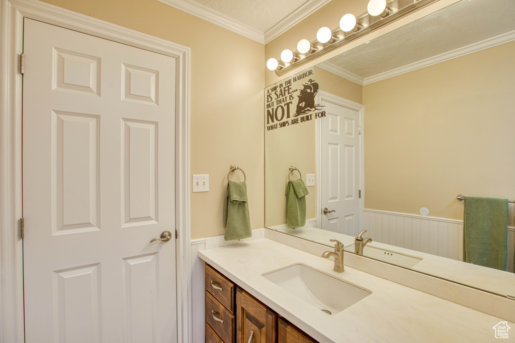 Bathroom featuring vanity, wainscoting, and crown molding