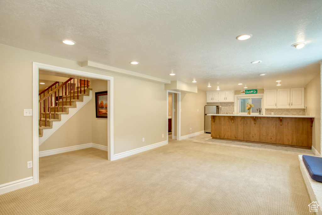 Unfurnished living room featuring recessed lighting, light carpet, and stairs