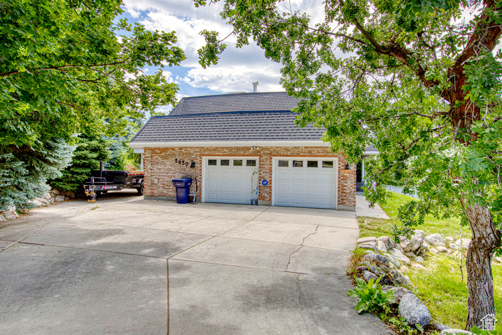 View of side of property featuring concrete driveway, a garage, and brick siding