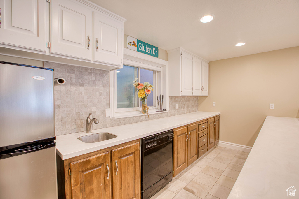 Kitchen with freestanding refrigerator, black dishwasher, backsplash, light countertops, and recessed lighting