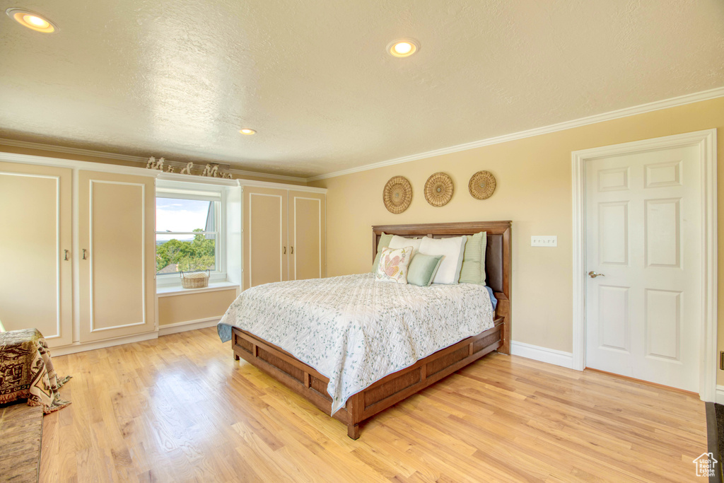 Bedroom featuring light wood-style floors, ornamental molding, and recessed lighting