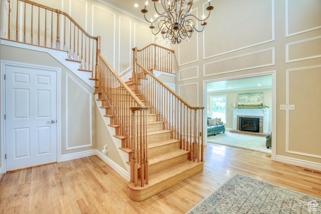 Stairway with a decorative wall, wood finished floors, a chandelier, and a fireplace