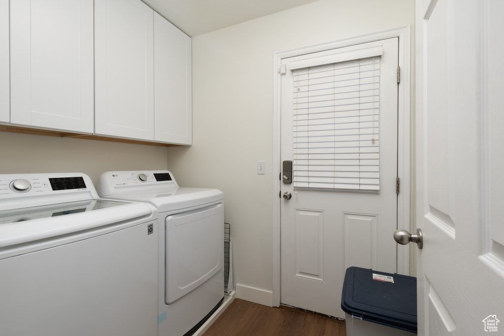 Laundry room featuring washing machine and dryer, cabinet space, and dark wood finished floors
