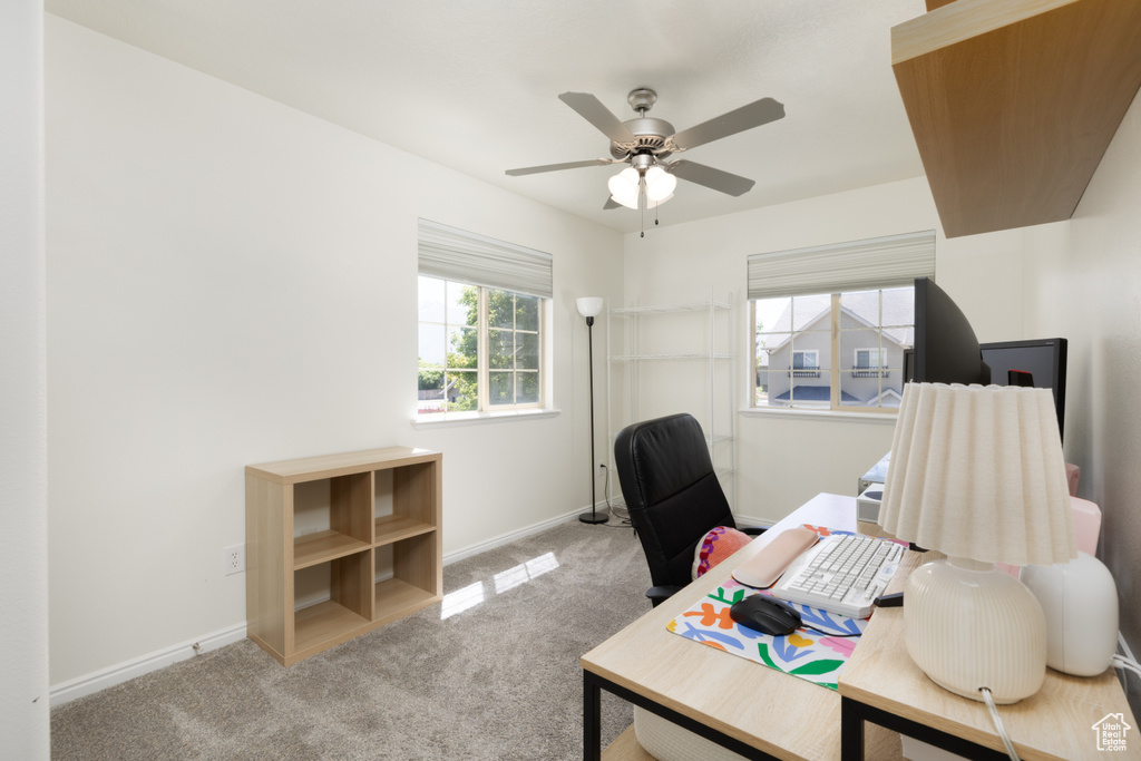 Carpeted office featuring a ceiling fan and baseboards