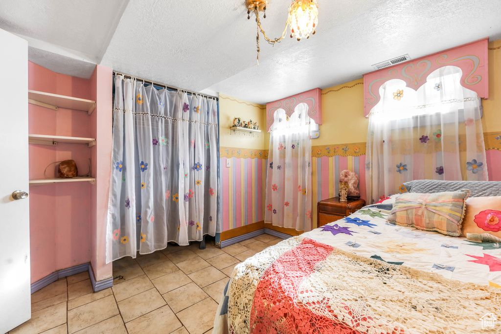 Tiled bedroom with a textured ceiling and wallpapered walls