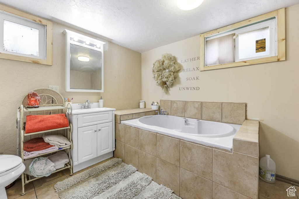 Bathroom featuring tile patterned floors, a bath, and vanity