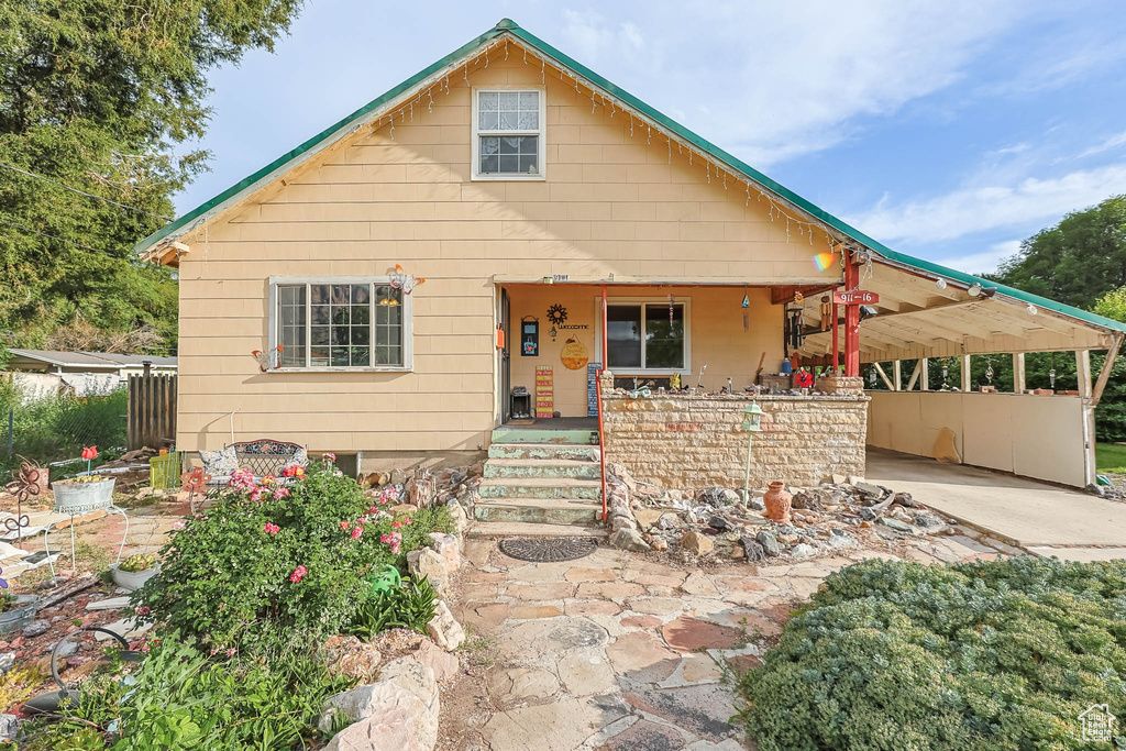 Bungalow-style house featuring a porch, an attached carport, and concrete driveway
