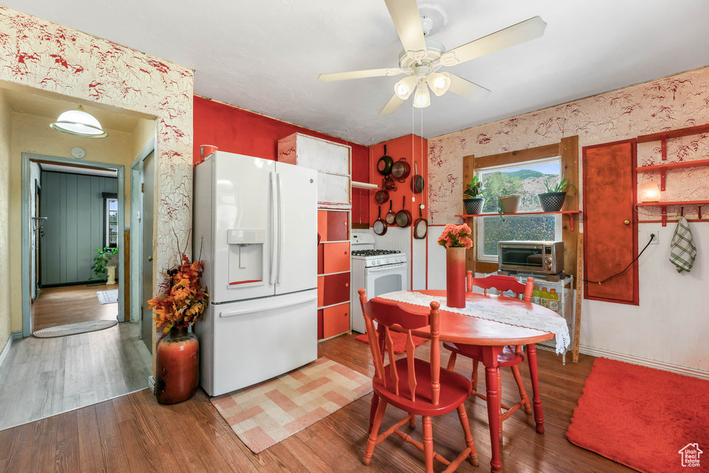 Dining area with a ceiling fan, wood finished floors, and wallpapered walls