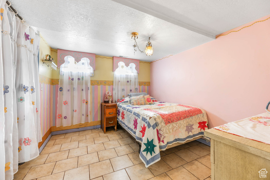 Bedroom with wainscoting, a textured ceiling, and tile patterned flooring