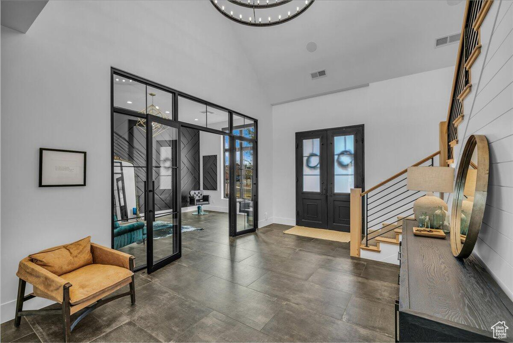 Entryway with french doors, stairs, high vaulted ceiling, and a chandelier