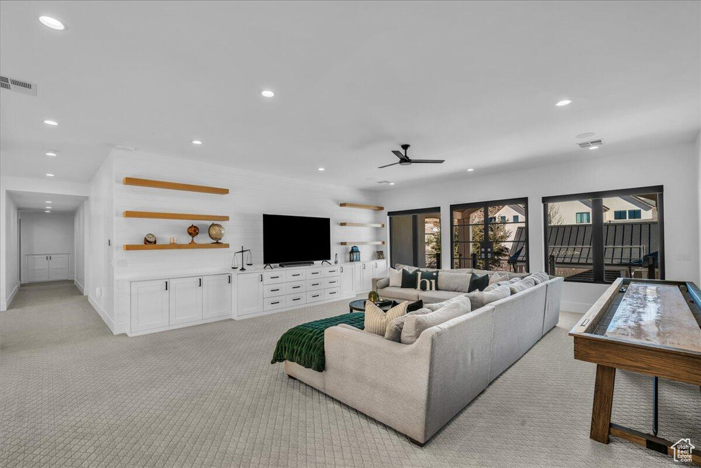 Living room with light colored carpet, recessed lighting, and a ceiling fan