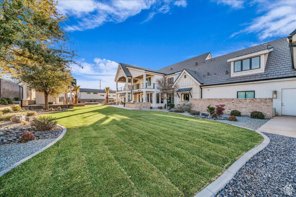 Rear view of property featuring a balcony and a yard