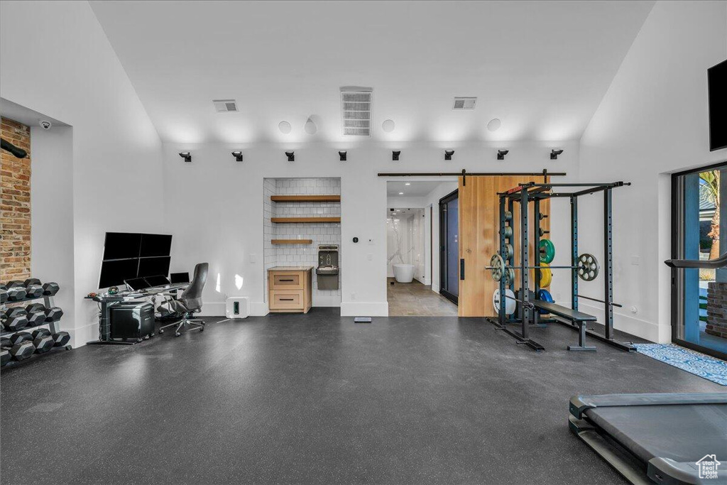 Exercise room featuring a barn door and a towering ceiling