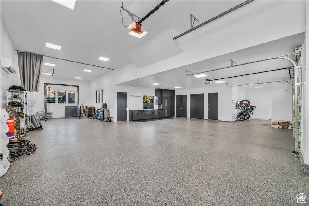 Garage featuring a wall mounted air conditioner and a garage door opener