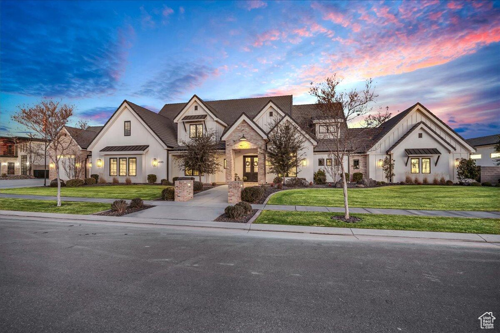 French country home with stone siding, board and batten siding, a yard, a standing seam roof, and stucco siding