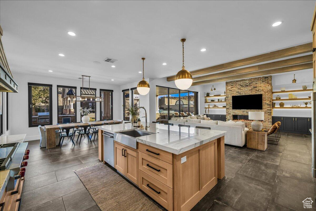 Kitchen with recessed lighting, dishwasher, a center island with sink, a fireplace, and decorative light fixtures