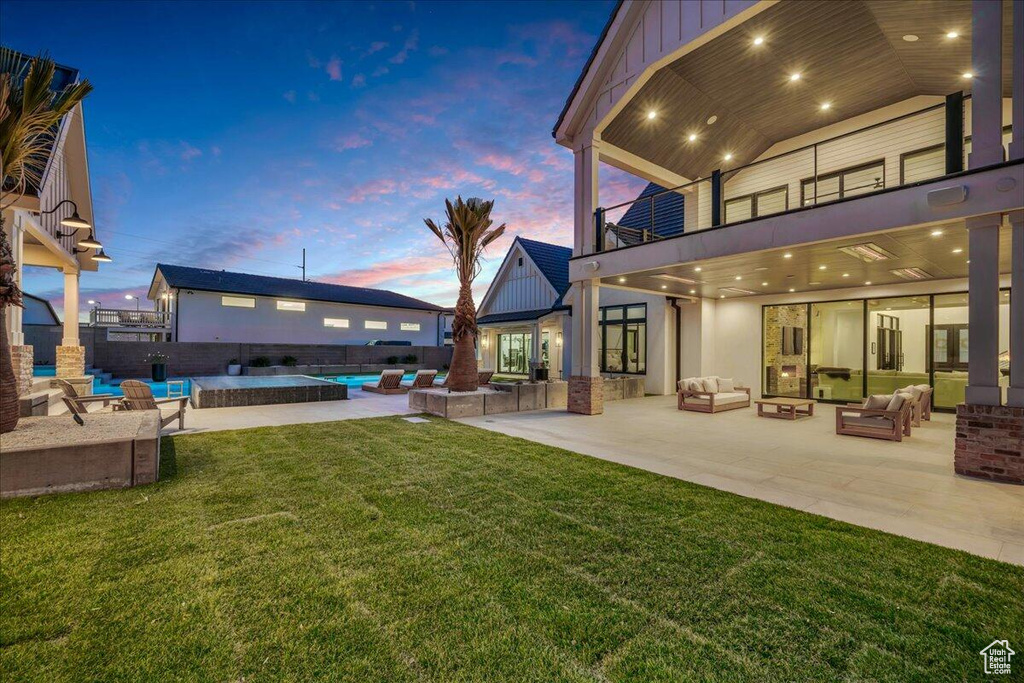 Fenced backyard featuring a balcony, an outdoor living space, a patio area, and an outdoor pool